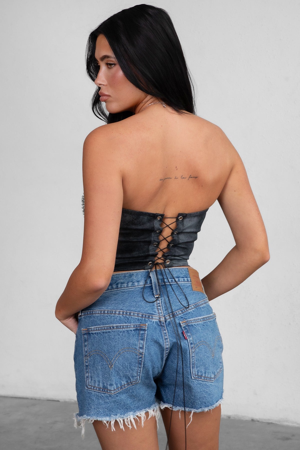 TIC TOC TA29069 BECKEE PU Vegan Leather Corset Top in distressed leather. Features a straight strapless neckline, rhinestone western detail, and lace-up back in color black. 