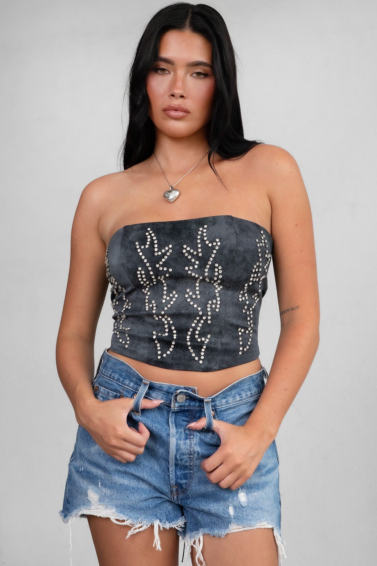 TIC TOC TA29069 BECKEE PU Vegan Leather Corset Top in distressed leather. Features a straight strapless neckline, rhinestone western detail, and lace-up back in color black. 