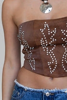 TIC TOC TA29069 BECKEE PU Vegan Leather Corset Top in distressed leather. Features a straight strapless neckline, rhinestone western detail, and lace-up back in color brown. 