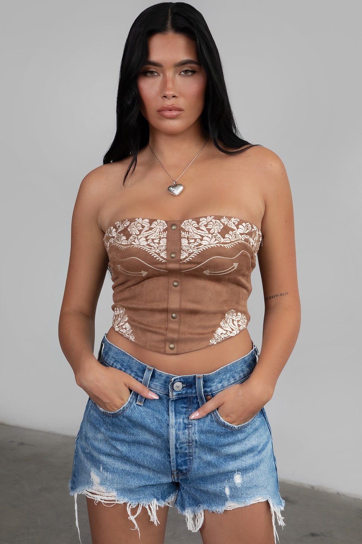 TIC TOC TA30268 MONTANA Embroidered Suede Bustier Top in soft suede with floral embroidery, button-front closure, and asymmetrical hem. Western-inspired festival top