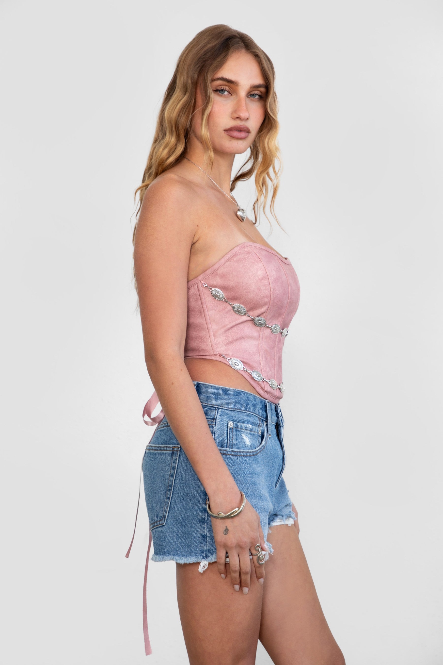 TIC TOC TA30530 GLENDORA Distressed PU Leather Corset Top in blush. Features a sweetheart neckline, boned structure, silver western embellishments, and an adjustable satin lace-up back.