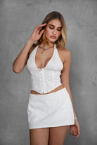 TIC TOC TC30798 ANNEE NERISSA Eyelet Embroidered Halter Bustier Top in white. Features floral eyelet embroidery, adjustable halter neckline, V-neckline, asymmetrical hem, and hook-and-eye closure.