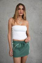 COLBI Essentials Plush Fleece Mini Skort with ribbed tie waistband and contrast piping in pine green.