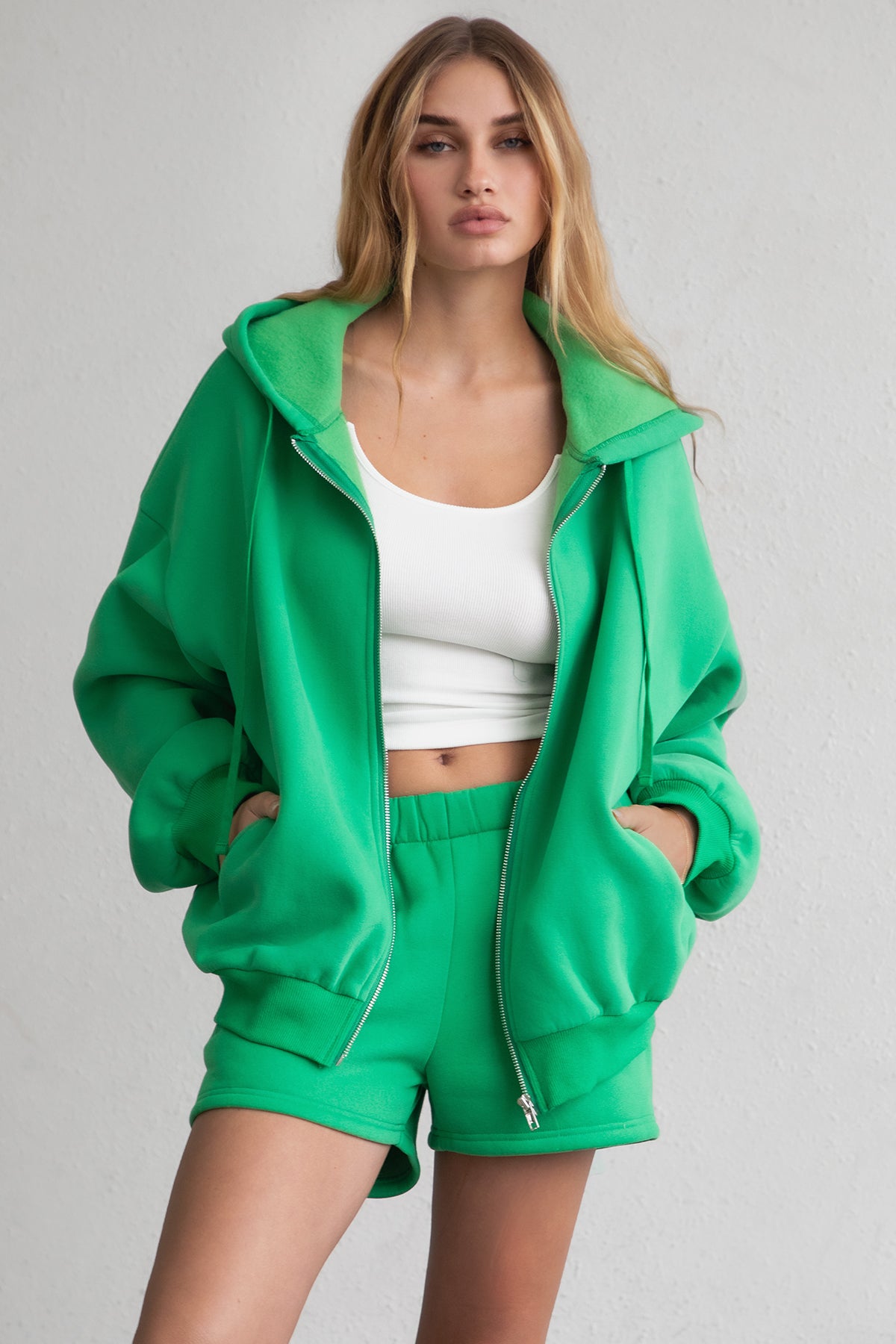 Bright green zip-up hoodie with smooth fleece fabric and side welt pockets for storage by Tic Toc.